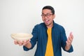 Adult Asian man looking at empty bowl that he hold with excited expression Royalty Free Stock Photo
