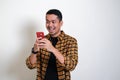 Adult Asian man showing surprised face expression while read message in his mobile phone Royalty Free Stock Photo