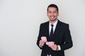 Adult Asian man wearing black suit and tie holding paper money while showing happy face expression Royalty Free Stock Photo
