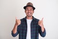 Adult Asian man wearing classic hat smiling happy and giving two thumbs up