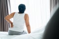 Adult Asian woman is sitting on the bed and holding her lower back suffering from injured back. Health care and back pain concept Royalty Free Stock Photo