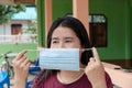 Adult Asian woman wearing medical face mask. Pretty middle female showing how to wear surgical medical mask step by step