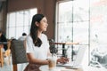 Adult asian woman in white shirt sitting at table with laptop Royalty Free Stock Photo