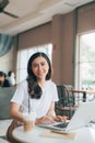 Adult asian woman in white shirt sitting at table with laptop Royalty Free Stock Photo