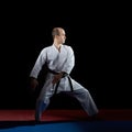 Adult athlete performs formal karate exercises on red and blue tatami