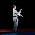 Adult athlete trains formal karate exercises on red and blue tatami
