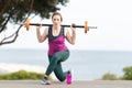 Adult athletic woman training her hands using a dumbbell outdoors near the sea Royalty Free Stock Photo