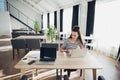 Adult attractive woman on her work is holding phone and sitting with a laptop. Beautiful female multitasking. Royalty Free Stock Photo