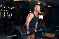 Adult bald Bodybuilder muscular man doing heavy deadlift exercise with weight while in gym in dark Royalty Free Stock Photo