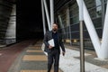 an adult bearded businessman with a laptop in his hands walks outside along the office building Royalty Free Stock Photo