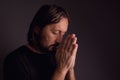 Adult bearded man praying in dark room Royalty Free Stock Photo