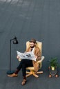 adult bearded man reading business newspaper in armchair