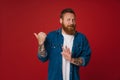 Adult bearded tattooed handsome disgusted redhead man pointing aside