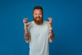 Adult bearded tattooed handsome stylish insidious man with raised hands