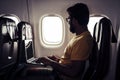 Adult bearded traveler man sitting inside the aircraft and flight to destination - computer with wifi internet connection on board Royalty Free Stock Photo