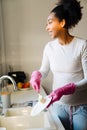 Adult beautiful pregnant african woman washing dishes in cozy kitchen Royalty Free Stock Photo