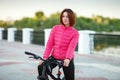 Adult beautiful redhead woman with bob haircut posing on bicycle in autumn city river pier Royalty Free Stock Photo