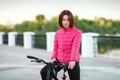 Adult beautiful redhead woman with bob haircut posing on bicycle in autumn city river pier Royalty Free Stock Photo