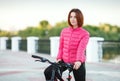 Adult beautiful redhead woman with bob haircut posing on bicycle in autumn city river pier Royalty Free Stock Photo