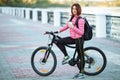 Adult beautiful redhead woman with bob haircut thinking drinking morning coffee posing on bicycle in autumn city river pier Royalty Free Stock Photo