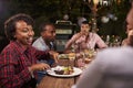 Adult black family enjoy dinner and conversation in garden