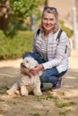 Adult blond woman walking with fluffy white dog in city park