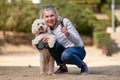 Adult blond woman walking with fluffy white dog in summer city