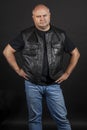 Adult brutal bald man in a leather jacket, dark background Royalty Free Stock Photo