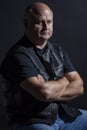 Adult brutal bald man in a leather jacket, dark background