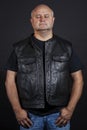 Adult brutal bald man in a leather jacket, dark background Royalty Free Stock Photo