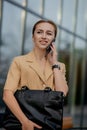 Adult Caucasian Confident Young Business Woman is Talking on Phone Outside near Modern Office Building Royalty Free Stock Photo