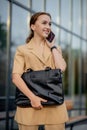 Adult Caucasian Confident Young Business Woman is Talking on Phone Outside near Modern Office Building Royalty Free Stock Photo