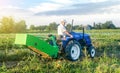 A adult caucasian farmer driver on a farm tractor drives to the field to harvest potatoes. Agro industrial technologies. Growing Royalty Free Stock Photo