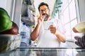 Adult caucasian man taking note list of food looking inside the open fridge at home - kitchen activity and alternative point of Royalty Free Stock Photo