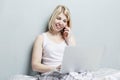 An adult Caucasian woman in her pajamas is excited to have found good news on the Internet using a laptop while making a call on a Royalty Free Stock Photo