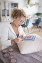 Adult caucasian woman at home doing crochet hobby activity at home decorating a shabby chic white pillow. Living room interior in