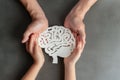 Adult and child hands holding encephalography brain paper cutout, autism, Stroke, Epilepsy and Alzheimer awareness