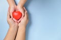 Adult and child hands holding red heart  on blue background Royalty Free Stock Photo