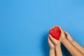 Adult and child hands holding red heart over blue background. Love, healthcare, family, insurance, donation concept Royalty Free Stock Photo