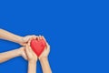 Adult and child hands holding red heart over blue background. Love, healthcare, family, help, insurance, donation Royalty Free Stock Photo