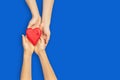 Adult and child hands holding red heart over blue background. Love, healthcare, family, insurance, donation concept Royalty Free Stock Photo