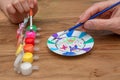 Adult and child hands painting a dish with a brush and a set of paint