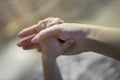 Adult and child hands together. Adult caucasian woman arm holds little child hand on blurred background. Local focus, care and ten Royalty Free Stock Photo