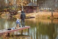 Adult and child on a wooden pier, fishing bridge. Autumn park. Fallen leaves, sunny day, natural background.