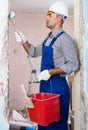 adult concentrated man repairer working with roller in uniform, gloves and helmet