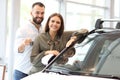 Adult couple choosing new car in showroom