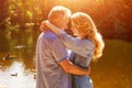 An adult couple stand on the shore of the lake in an embrace in the rays of the setting sun Royalty Free Stock Photo