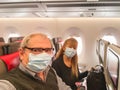 Adult couple taking a selfie while travelling by plane wearing a surgical mask during the covid pandemic Royalty Free Stock Photo