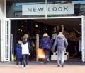 An adult couple and two children walking into a New Look shop