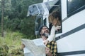 Adult couple use map guide to choose next travel destination enjoying freedom and vacation outside a modern camper van. Nomadic